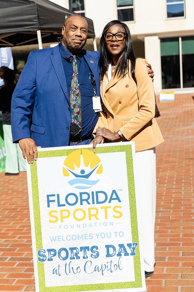 Guests holding a Florida Sports Foundation sign welcoming visitors to Sports Day at the Capitol